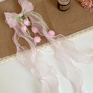 Vista dettagliata di un fermaglio per capelli con fiocco in organza rosa e fiori
