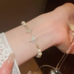 Detailed view of an 18k gold-plated starburst bracelet with white pearls and zircons.