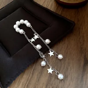 Elegant minimalist pearl tassel ear cuff with star charms on black velvet jewelry display pad