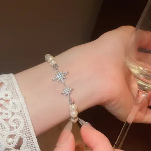 Detailed view of an elegant zircon star and pearl bracelet worn on a female wrist.