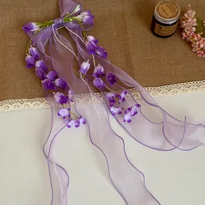 Dettaglio della molletta per capelli mughetto viola con eleganti nastri in organza viola chiaro
