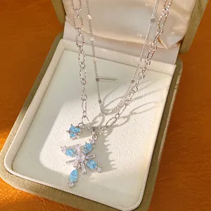 Detailed macro shot of silver double-layered necklace with blue and clear zircon cross pendant