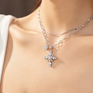 Detailed close-up of double layer silver necklace with blue zircon cross pendant