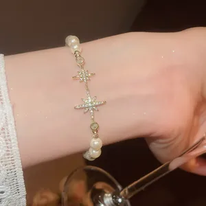Detail of 18k gold plated bracelet with sparkling star charms and elegant pearls