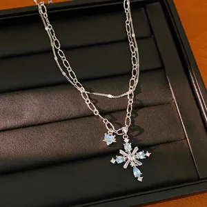 Detailed view of double-layered silver chain necklace with light blue zircon cross