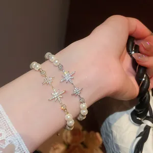 Close-up of elegant starburst pearl bracelets with 18k gold plating on a woman's wrist