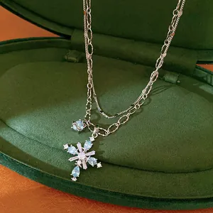 Detailed view of a double-layer silver chain necklace featuring a blue zircon cross pendant
