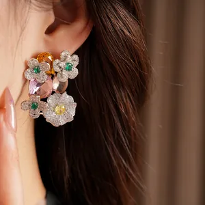 Macro detail of exquisite multicolor zircon flower and oval stud earrings worn on ear