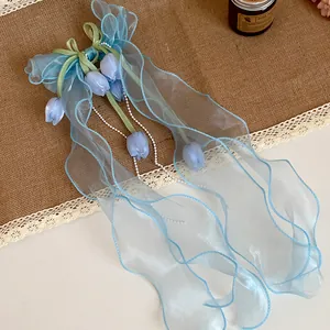Dettaglio di fermaglio per capelli a fiocco in organza azzurra con perle e fiori