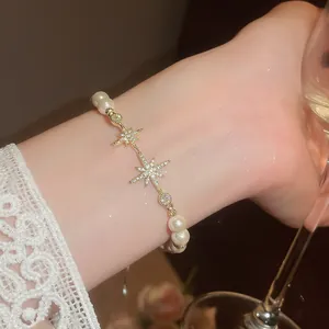 Detail of 18k gold plated bracelet with zircon stars and elegant pearls on wrist