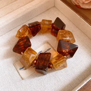 Close-up of Maillard style amber acrylic chunky geometric bead bracelet on cream fabric