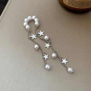 Close-up of pearl bead ear cuff with silver star charms and long chain tassels