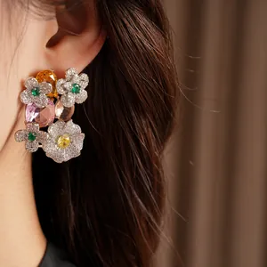 Close-up of vintage floral earrings with colorful zircons and large oval gemstones on model