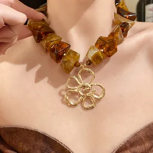 Detailed close-up of a vintage amber acrylic bead necklace featuring a gold textured flower pendant