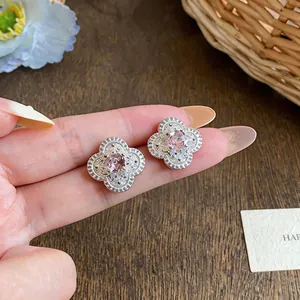 Dettaglio macro di orecchini a fiore in stile francese con eleganti zirconi rosa e bianchi