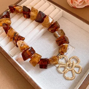 Detail view of vintage amber acrylic bead necklace with large gold flower pendant.