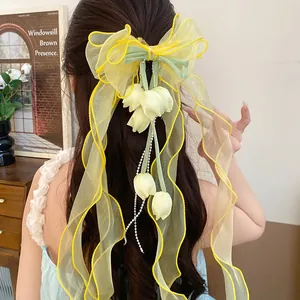 Vista dettagliata di un fermaglio per capelli con fiocco in organza giallo e mughetto