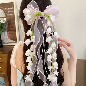 Vista dettagliata di un fiocco rosa con mughetto e perle per capelli su una modella
