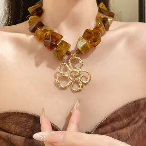 Close-up of vintage Maillard style amber acrylic bead necklace featuring a gold flower pendant