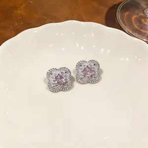 Orecchini a lobo fiore stile francese con zircone rosa, dettaglio su piatto di ceramica