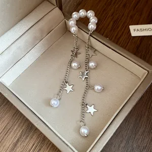 Close-up of elegant pearl and silver star tassel ear cuff inside a luxury jewelry box