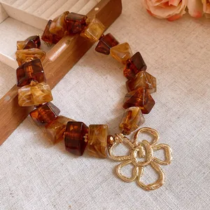 Close-up of retro amber acrylic bracelet with a gold textured flower charm