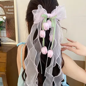 Dettaglio di una molletta per capelli con fiocco rosa e dolci decorazioni di mughetto