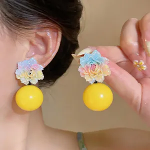 Close-up of vibrant gradient resin flower earrings with large yellow ball drop detail.