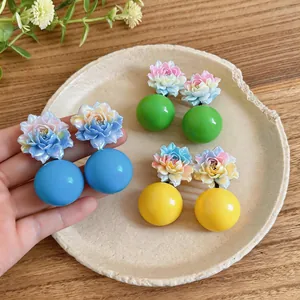 Close-up of colorful resin flower earrings featuring vibrant blue green and yellow balls