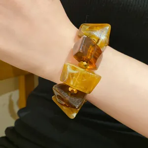 Detailed macro view of a vintage amber acrylic geometric block bracelet worn on a wrist