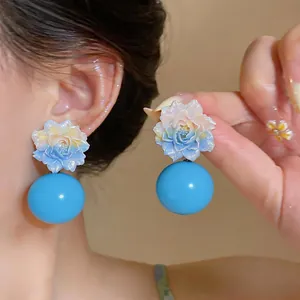 Detailed macro view of elegant blue resin flower earrings with large glossy ball pendants