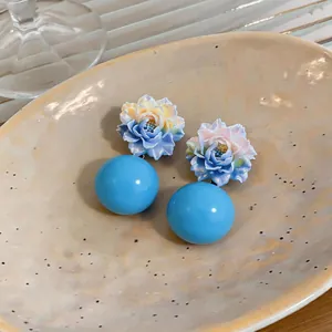 Close-up view of blue gradient flower resin earrings with large light blue spheres.