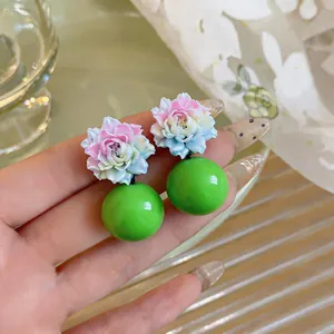 Close-up detail of resin flower earrings with pink gradient petals and green ball drops