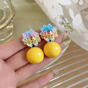 Close-up of resin gradient flower earrings with bright yellow round bead drops.