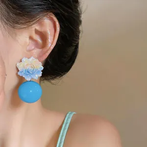Detailed close-up of a blue resin flower stud earring featuring a large spherical drop