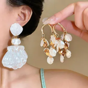 Close-up of elegant French palace style shell and petal fringe drop earrings.