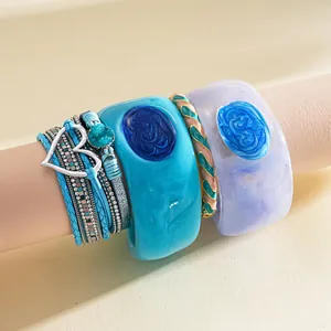 Macro detail of layered teal leather bracelet set with resin cuffs and silver heart