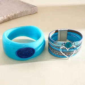 Detailed view of a blue resin bangle paired with a multilayer leather heart bracelet