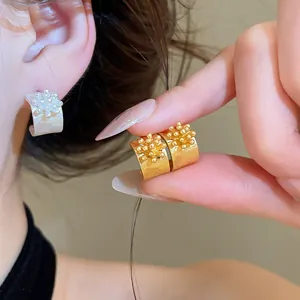 Dettaglio di eleganti orecchini a lobo a forma di C con fiori in oro e argento indossati.