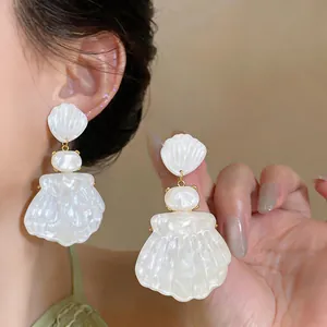 French style white pearlescent shell drop earrings on model for elegant vacation look