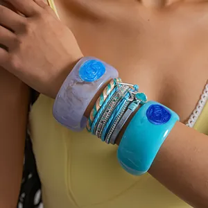 Detailed macro view of blue resin bangles and multi-layer heart charm leather bracelet.