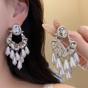 Close-up of retro silver earrings with oval rhinestones and elegant pearl tassels