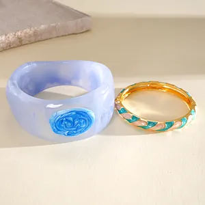 Detailed close-up showing a blue marbled resin bangle and a gold enamel wave bracelet