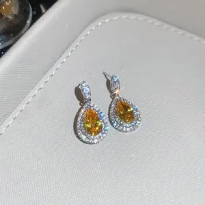 Detailed close-up of luxury yellow pear-cut zircon earrings featuring a sparkling halo effect