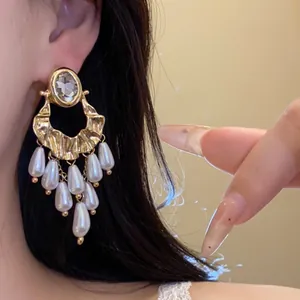 Detailed close-up of vintage gold tassel earrings with pearls and crystal worn on an ear.