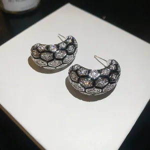 Detailed view of 18k gold plated C-hoop earrings with hexagonal zircon grid pattern
