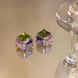 Macro view of multi-colored cube zircon stud earrings with silver-toned prongs