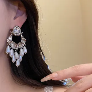 Close-up detail of vintage silver stud earring with rhinestones and pearl tassels.