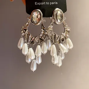 Close-up detail of vintage silver earrings featuring oval rhinestones and pearl tassels