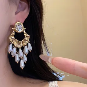 Close-up detail of elegant vintage gold tassel earrings with oval crystal and white pearl drops